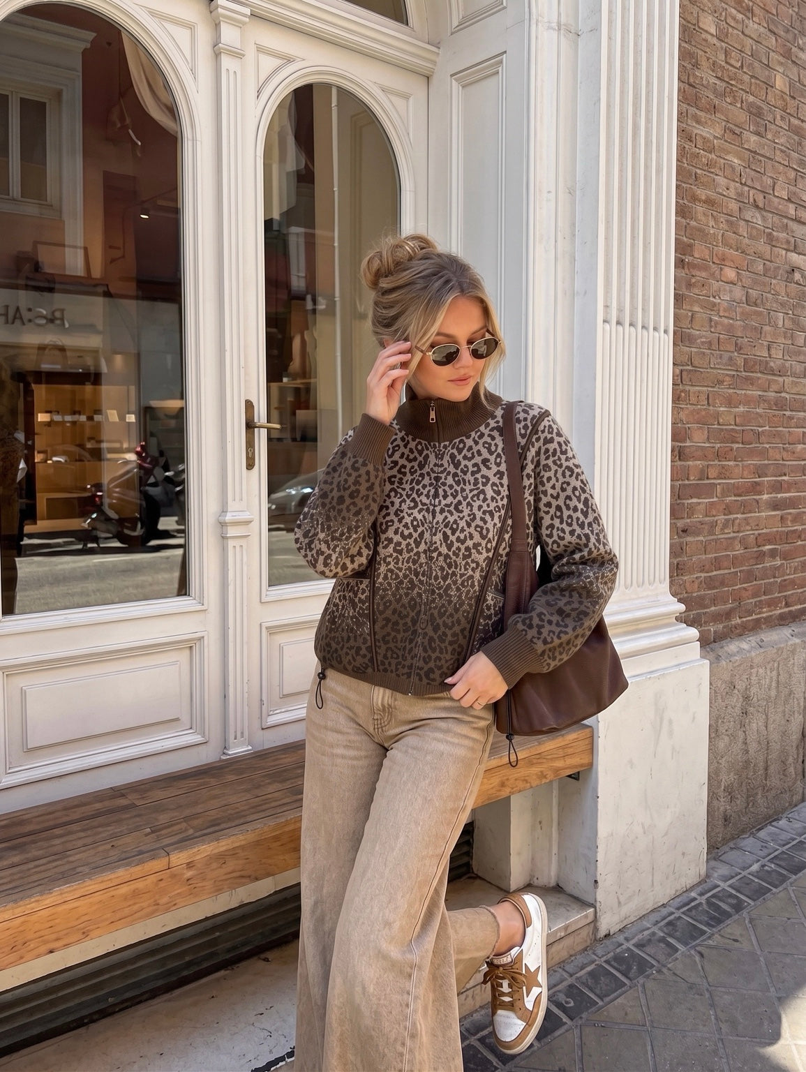 Veste LÉOPALIA en maille léopard beige et chocolat, col montant et fermeture zippée, portée avec un jean beige.